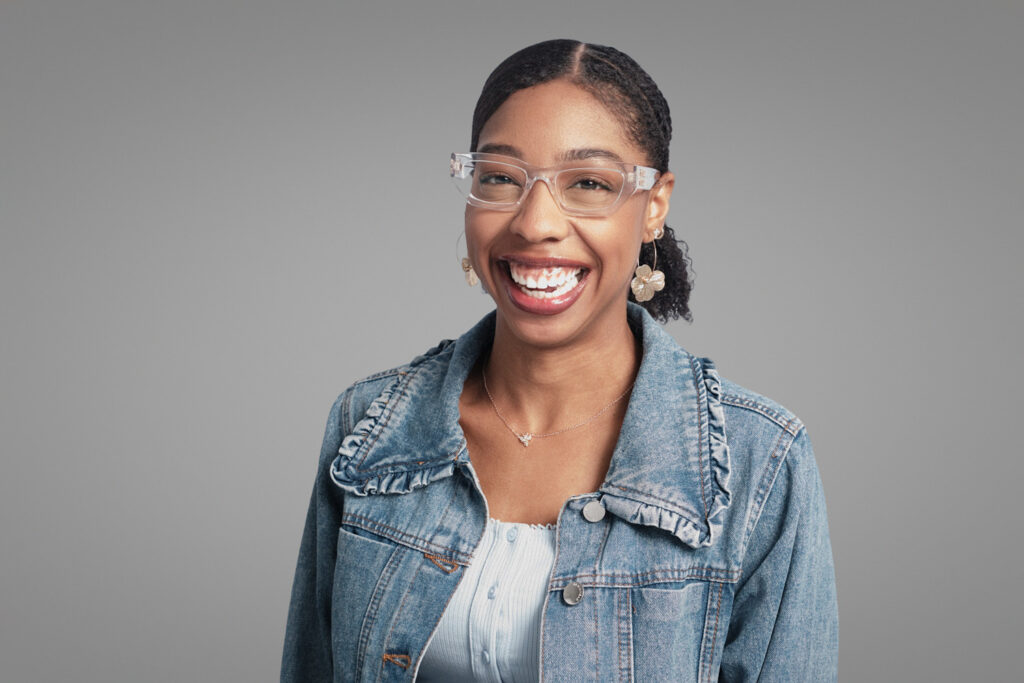 Smiling woman in denim jacket and glasses, relaxed professional headshot in Boston