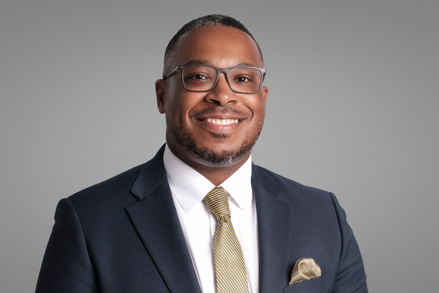 Corporate man in suit and gold tie smiling confidently, headshot by Boston photographer